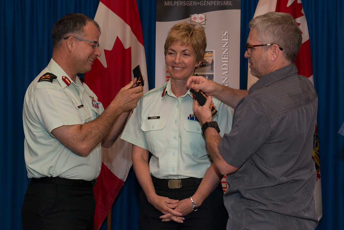 Brigadier-General Jennie Carignan (center) is promoted by Major-General Eric Tremblay (left) and  her husband Eric Lefrançois.